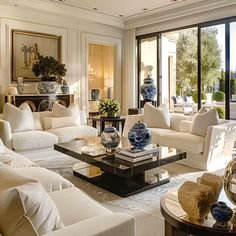 a living room filled with white furniture and large windows