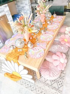 the table is set with pink and orange plates, silver vases, and flowers