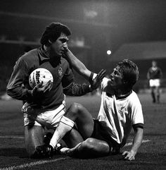 two soccer players are on the ground with their hands over each other's face