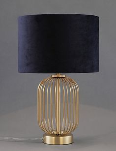 a gold metal table lamp with a black shade on the base and a blue lampshade