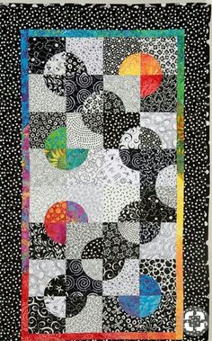 a black and white quilt with different colored circles on it's side, in the middle