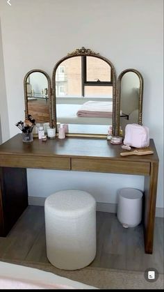 a dressing table with mirror, stool and ottoman next to it in a room that has white walls