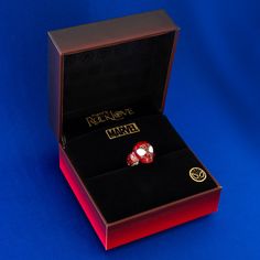 a red and black box with a ring in it on a blue tablecloth background