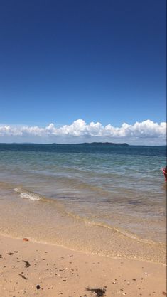 a person is standing on the beach holding a surfboard in their hand and looking out at the ocean