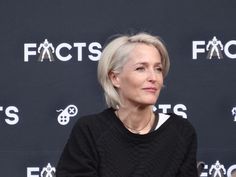 an older woman sitting in front of a black wall with the words fact's on it