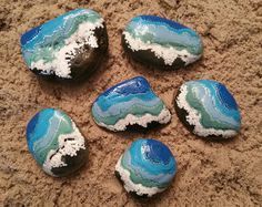 six blue and white rocks sitting in the sand