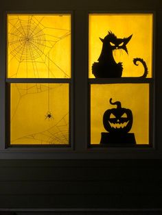 three windows with halloween decorations in them, one is yellow and the other is black