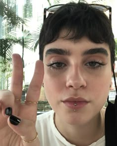 a person with eyeliners holding up two fingers in front of their face and making the peace sign