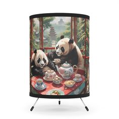 two pandas are sitting at a table with tea cups and saucers on it