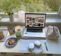 an open laptop computer sitting on top of a desk next to a plate of food