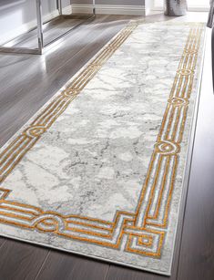 a white and yellow area rug with an intricate design on the floor in a living room