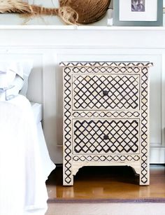 a white and black chest of drawers next to a wall with pictures on the walls