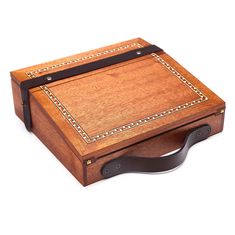 a wooden box with leather handles and beading on the sides, sitting on a white surface