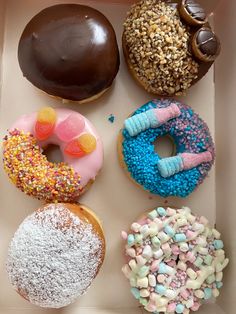 four donuts in a box with sprinkles and candy