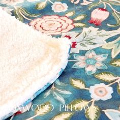 a white blanket laying on top of a blue flowered rug