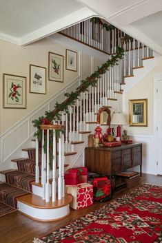 a staircase decorated for christmas with garland and presents under the bannister, along with other holiday decorations