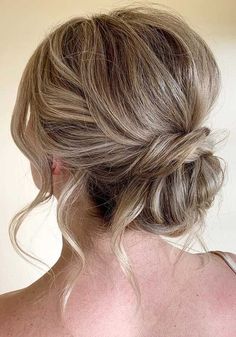 a woman with blonde hair wearing a white bra and braided updo is looking off to the side