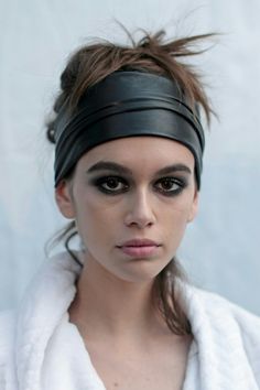 a woman wearing a white robe and black eyeliners with her hair in a bun