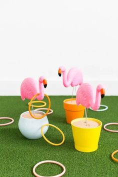 three pink flamingos are standing on top of two yellow and white pots with rings around them