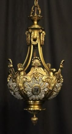 an ornate gold chandelier hanging from the ceiling in front of a black background