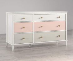 a white and pink dresser sitting on top of a hard wood floor