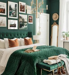 a bedroom with green walls and pictures on the wall above the bed, along with an ottoman