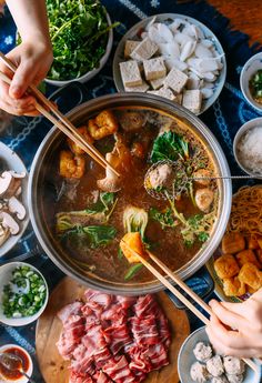 a table full of food with chopsticks sticking out of the meat and vegetables