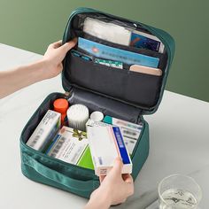 an open suitcase filled with medical supplies on top of a white table next to a glass of water