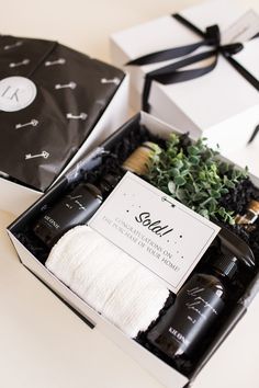 an open gift box with some items in it on a white table next to black and white boxes