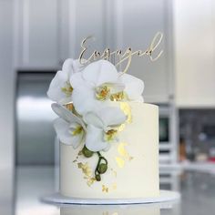 a white and gold wedding cake with flowers on it's top that says congratulations