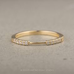 a yellow gold band with five diamonds on it, sitting on a gray surface in front of the camera