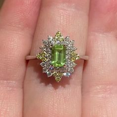 a woman's hand holding a ring with an emerald and white diamond in it