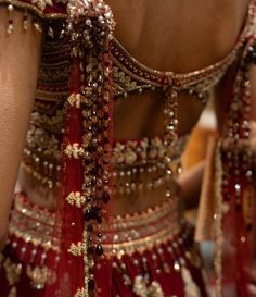 the back of a woman's dress with gold and red beads on her neck