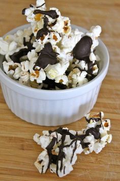 a bowl filled with chocolate covered popcorn on top of a wooden table