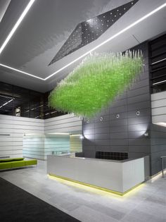 an office lobby with a green plant hanging from the ceiling and lights on the walls