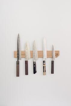 five knives are hanging on a wooden rack