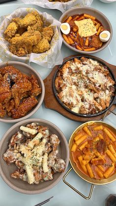 a table full of different types of food on plates and serving trays with chicken wings, fries, macaroni and cheese