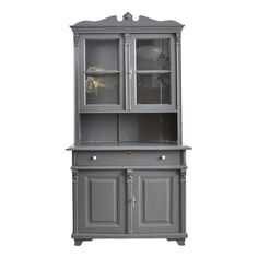 a gray china cabinet with glass doors on the top and bottom shelf, in front of a white background