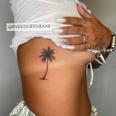 a woman's stomach with a small palm tree tattoo on it