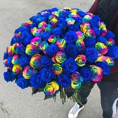 a person holding a large bouquet of colorful roses in their hands on the street,