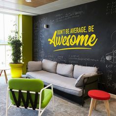 an office with chalkboard walls and colorful chairs in the corner, along with two couches