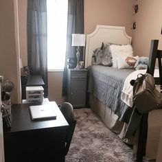 a bed room with a neatly made bed next to a desk and chair in front of a window