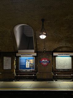 two benches sitting next to each other in a train station at night with the lights on