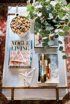 a table topped with lots of different items next to a potted plant on top of a metal tray