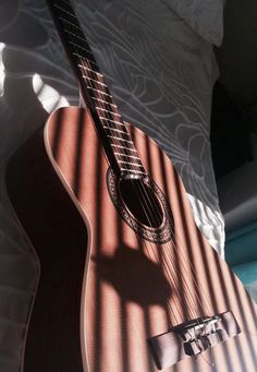 an acoustic guitar laying on top of a bed