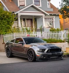 a silver mustang parked in front of a house