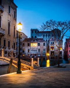 a street light sitting on the side of a road next to buildings and a bridge