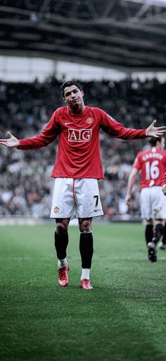 a man standing on top of a soccer field holding his hands out to the side