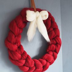 a red and white wreath hanging on the side of a wall with a wooden stick