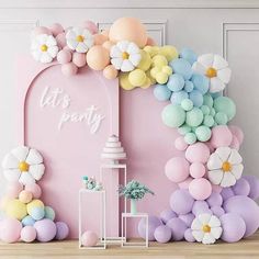 a pink backdrop with balloons and flowers on the wall is decorated in pastel colors